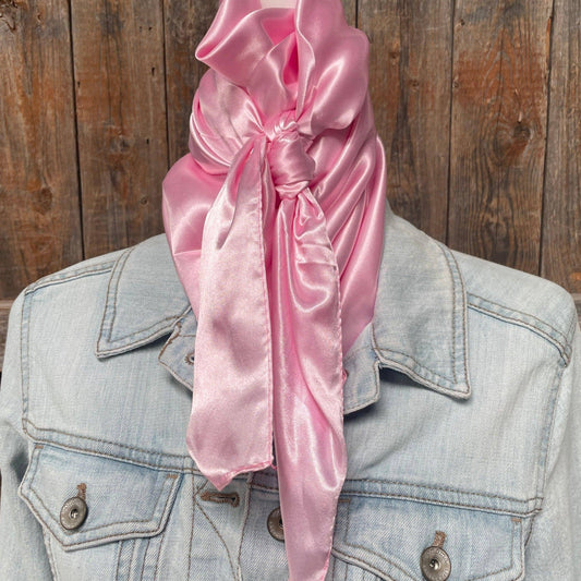 Pink satin scarf tied around a denim jacket against a wooden background