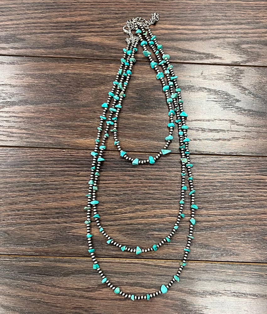 A handmade Navajo bead and turquoise necklace laid out on a wooden surface.