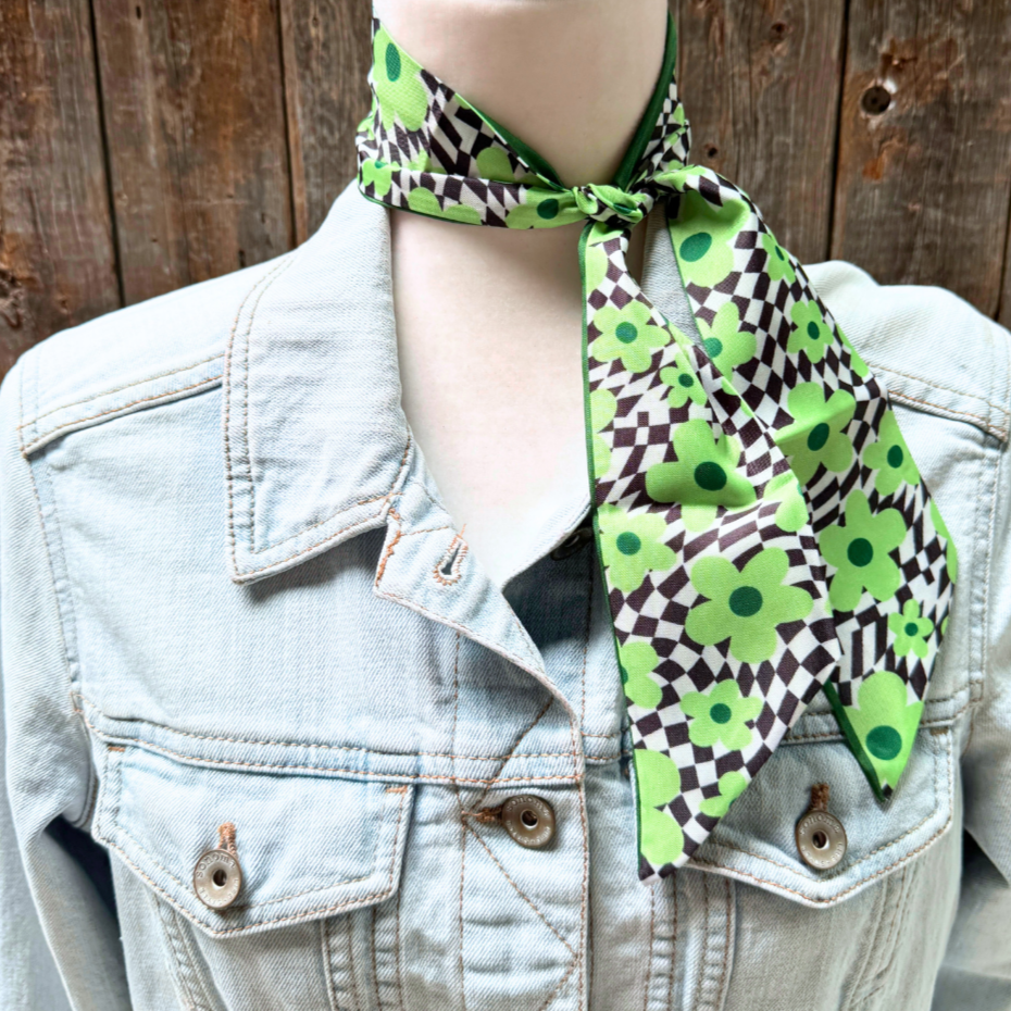 Mannequin wearing a green and black patterned scarf with a denim jacket.
