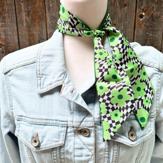 Mannequin wearing a green and black patterned scarf with a denim jacket.