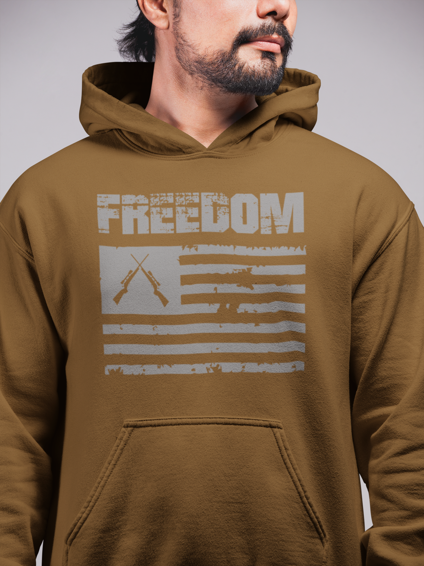 A person wearing a brown hoodie with the word 'FREEDOM' printed on the front in capital letters, with a stylized flag pattern behind the text.