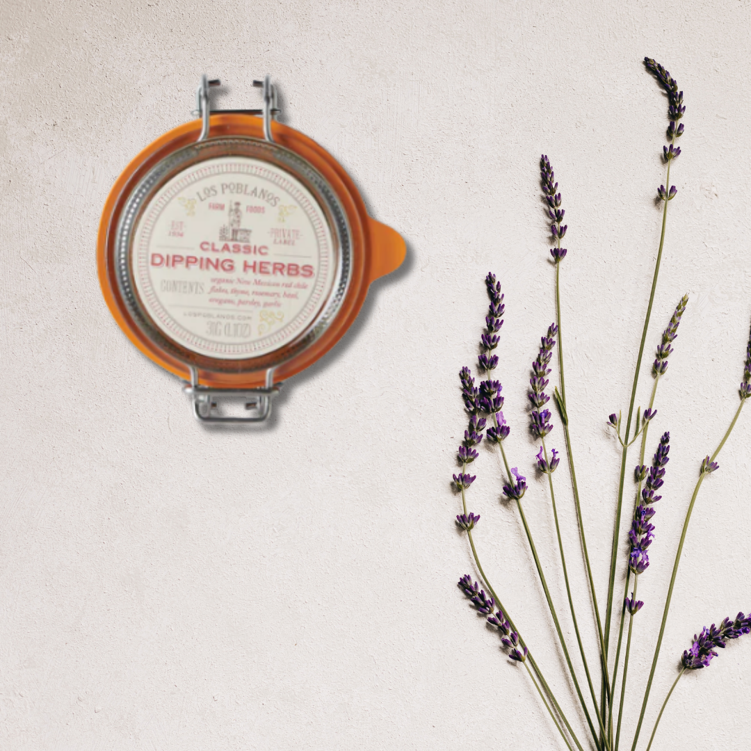 A reusable glass jar labeled 'Classic Dipping Herbs' with a content of dried herbs including thyme, rosemary, basil, oregano, and parsley, displayed next to a sprig of lavender.