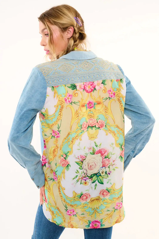 Woman wearing a floral patterned shirt with a blue long-sleeve shirt underneath on a white background