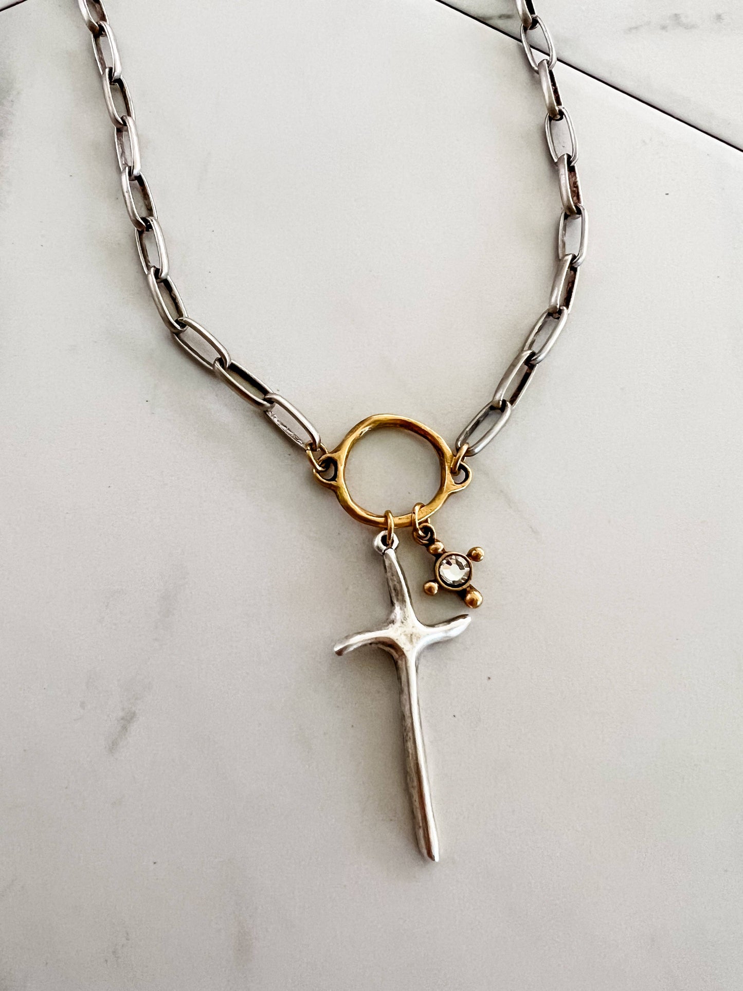 Necklace with a cross pendant and gold ring on a light background