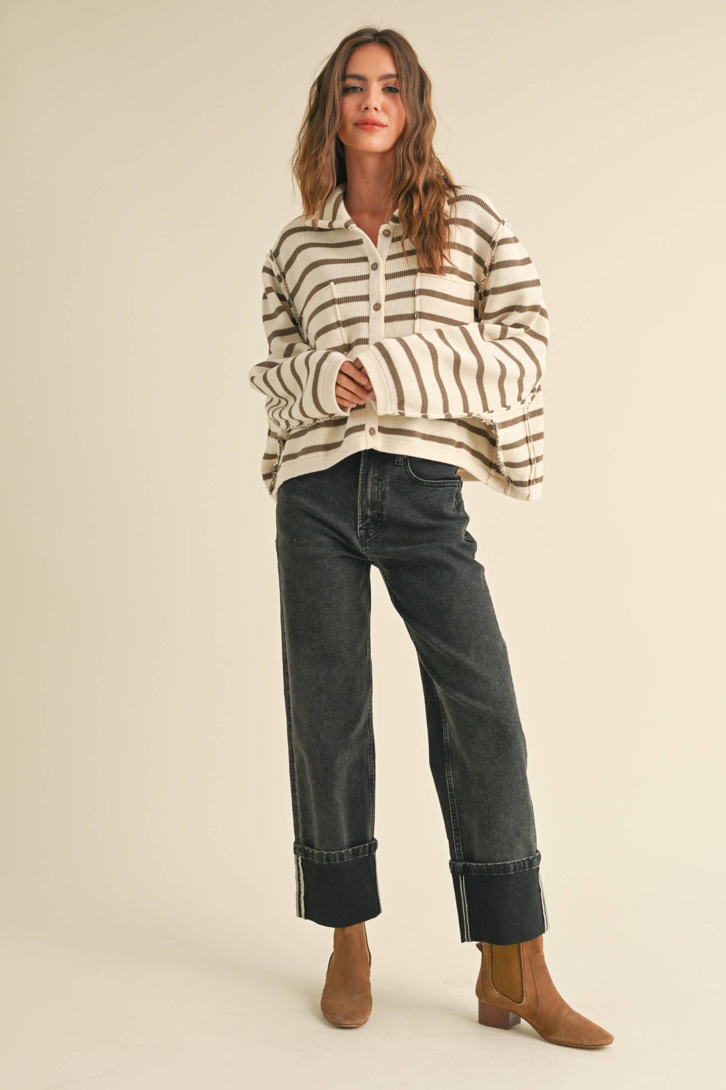 This image features a stylish woman sporting a casual yet trendy outfit, which includes a pair of cuffed black denim jeans and a striped pullover. The jeans are prominent, showcasing a classic design with a comfortable fit and stylish cuff detail, perfect for a relaxed yet fashionable look.