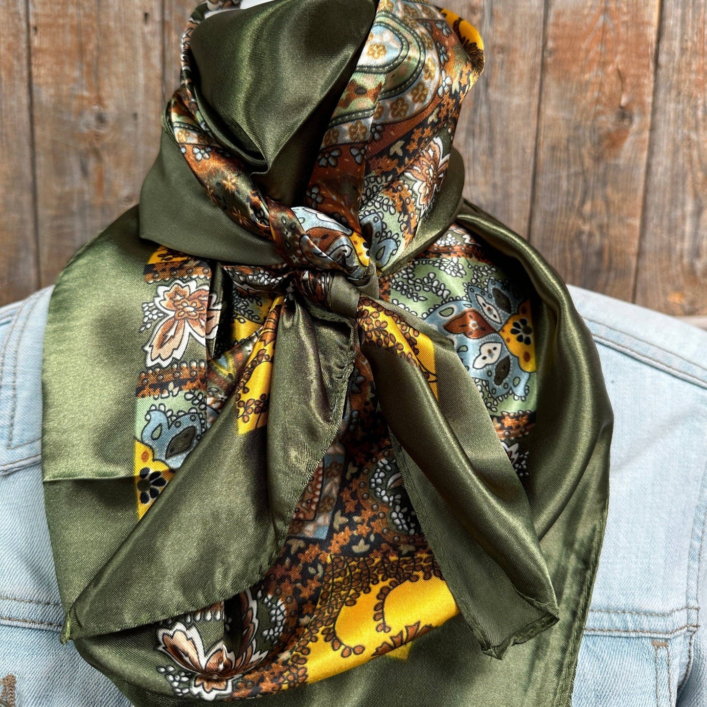 A green silk scarf with paisley patterns tied around the neck.
