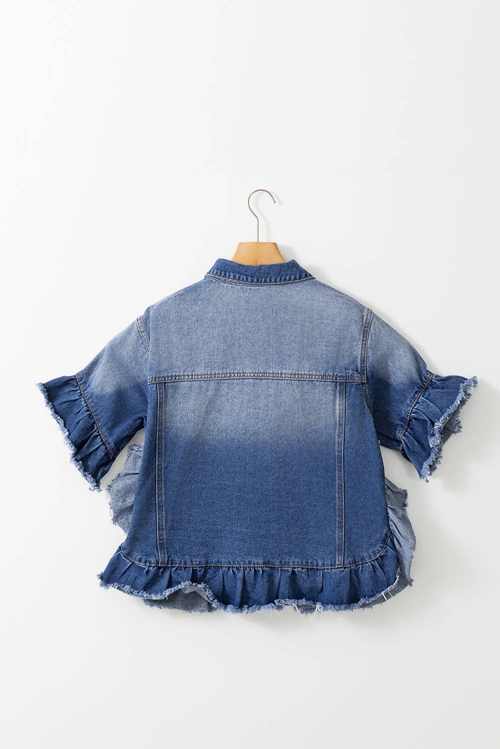 A woman wearing a blue denim jacket with short ruffled sleeves and a frayed hem.