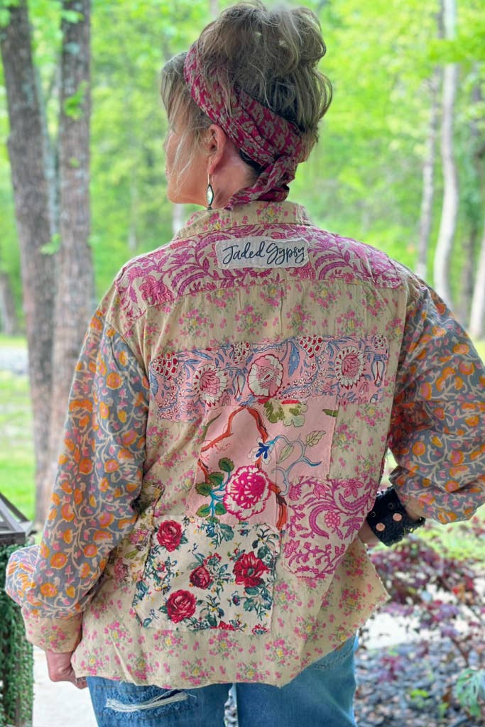 Woman wearing a floral and patchwork shirt outdoors with greenery in the background