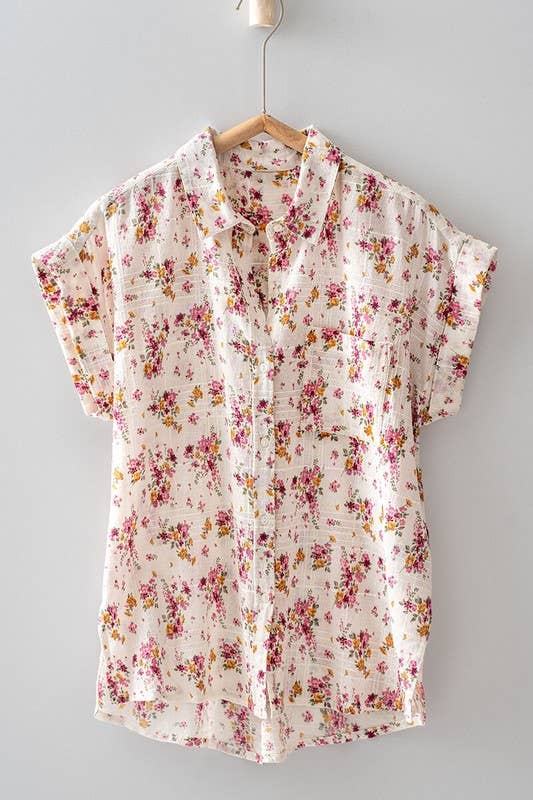 A white cotton shirt with a scattered rose print and cuffed sleeves, displayed on a hanger against a plain background.