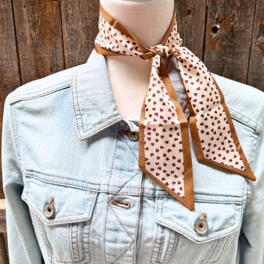 Mannequin wearing a denim jacket with a patterned scarf around its neck against a wooden background