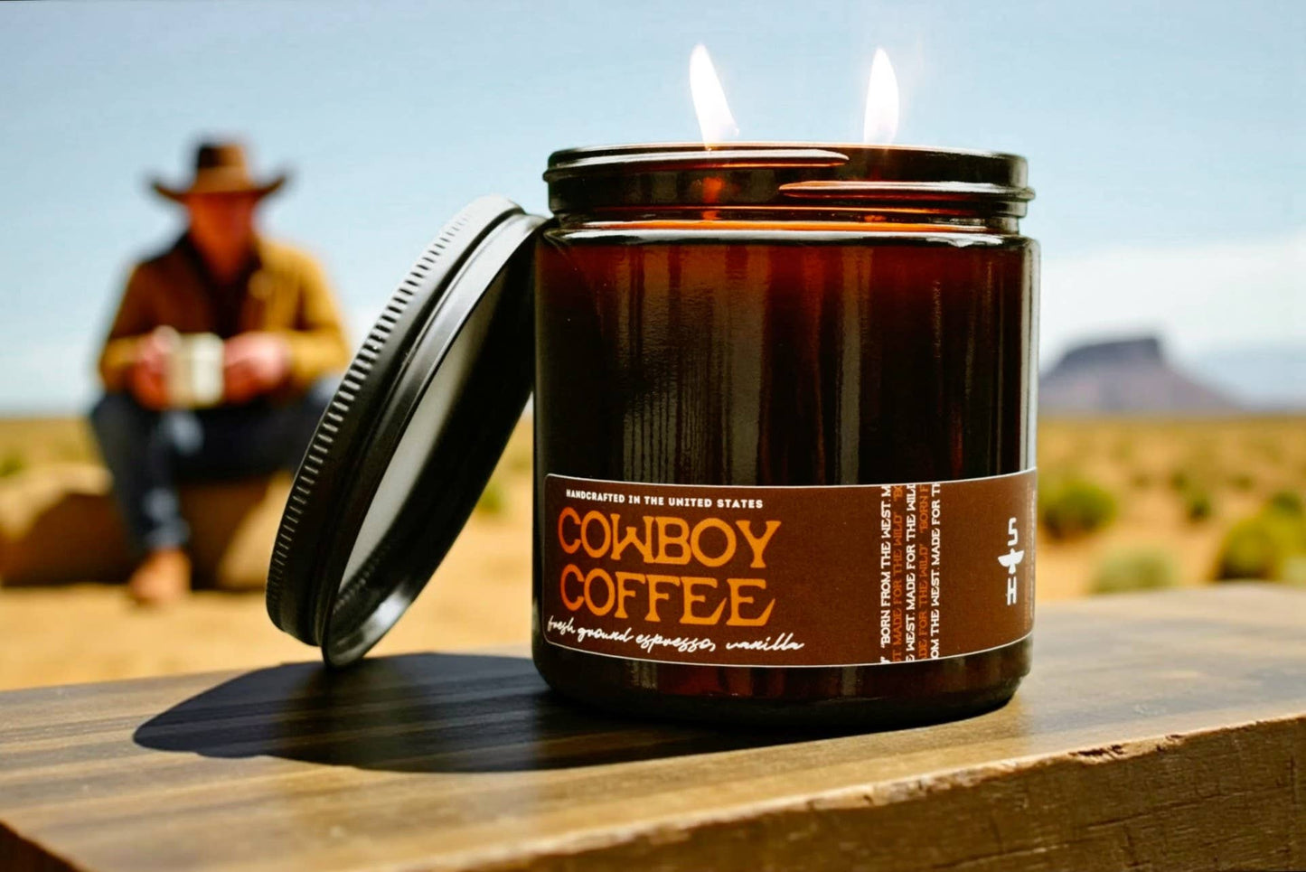 Candle labeled 'Cowboy Coffee' with a person in the background sitting on a rock.
