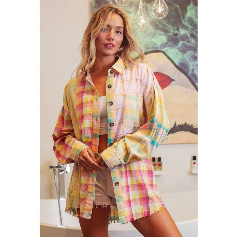 A person wearing a multicolored plaid shirt in a room with artistic wall decor.