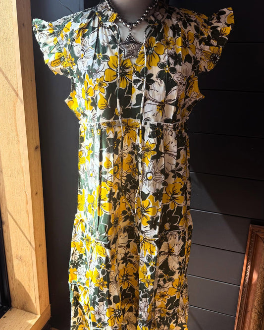 A floral midi dress displayed on a mannequin, featuring a mix of yellow, green, and white colors with a whimsical pattern.