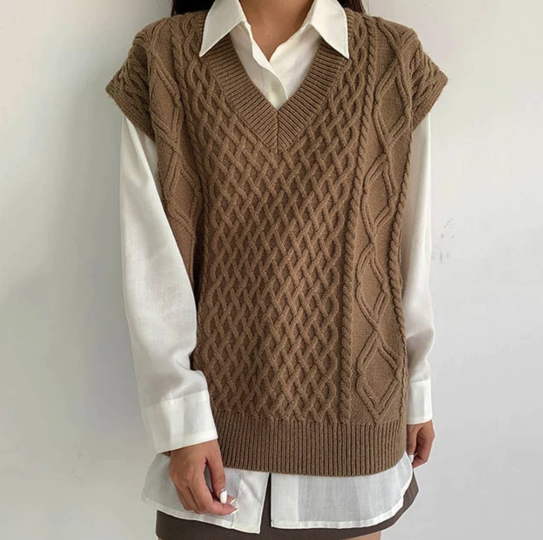 Brown knitted vest over a white shirt on a plain background