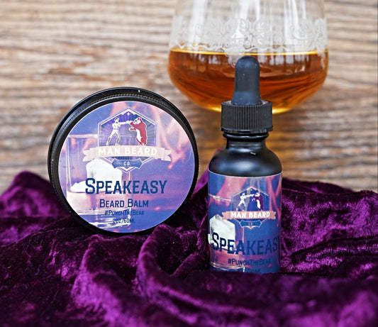 A glass with ice and a beard oil product inside, with the word 'Speakeasy' written on it, set against a backdrop with a warm, fiery appearance.
