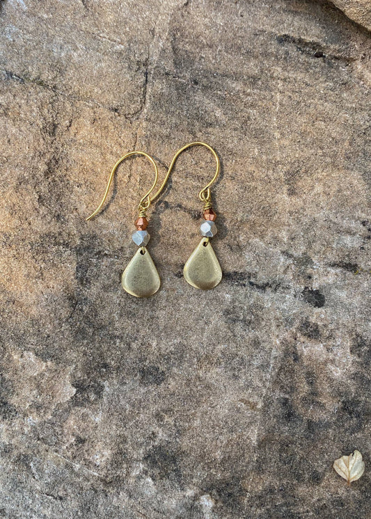 Pair of gold teardrop earrings with beads on a stone surface
