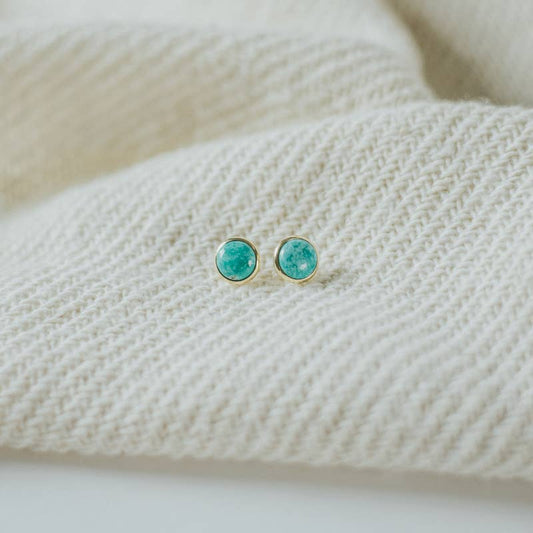 Turquoise stud earrings on a textured white surface
