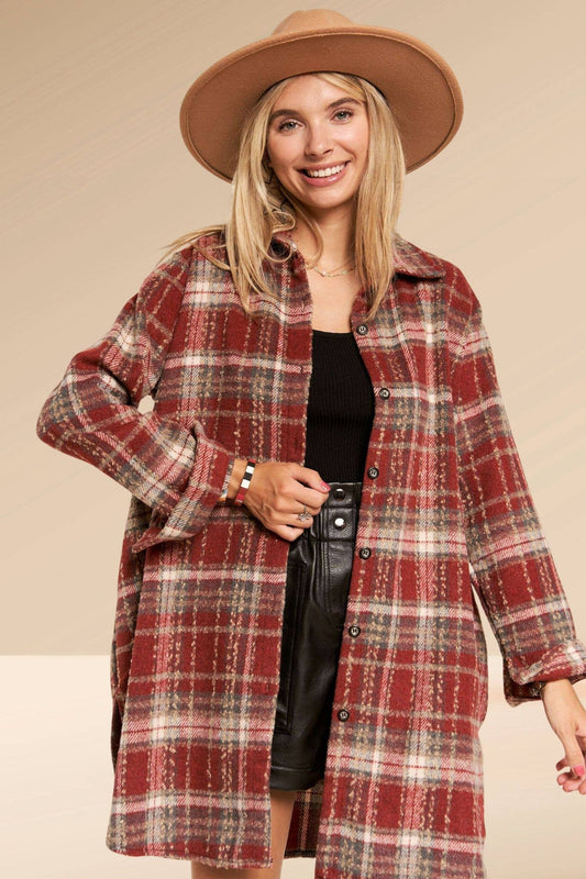 Woman wearing a red plaid coat and beige hat on a beige background
