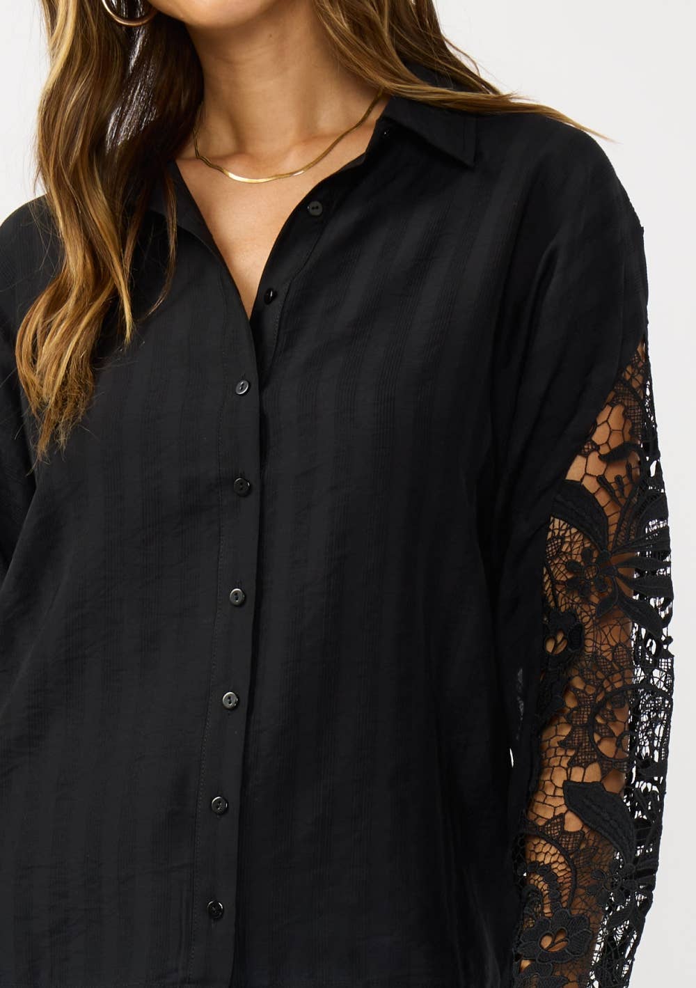 Black shirt with lace sleeves worn by a person on a white background