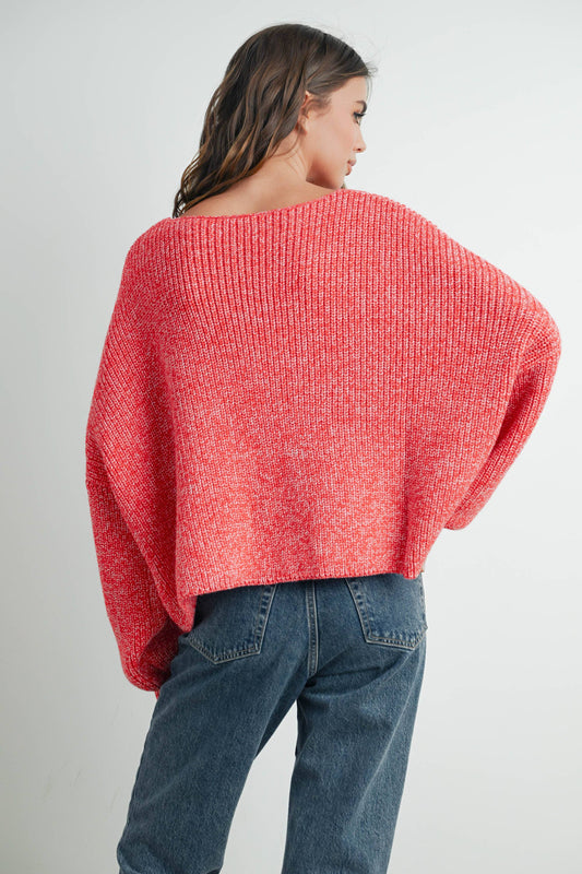 A woman wearing a red button down cardigan with a V-neck and long sleeves, paired with blue jeans.