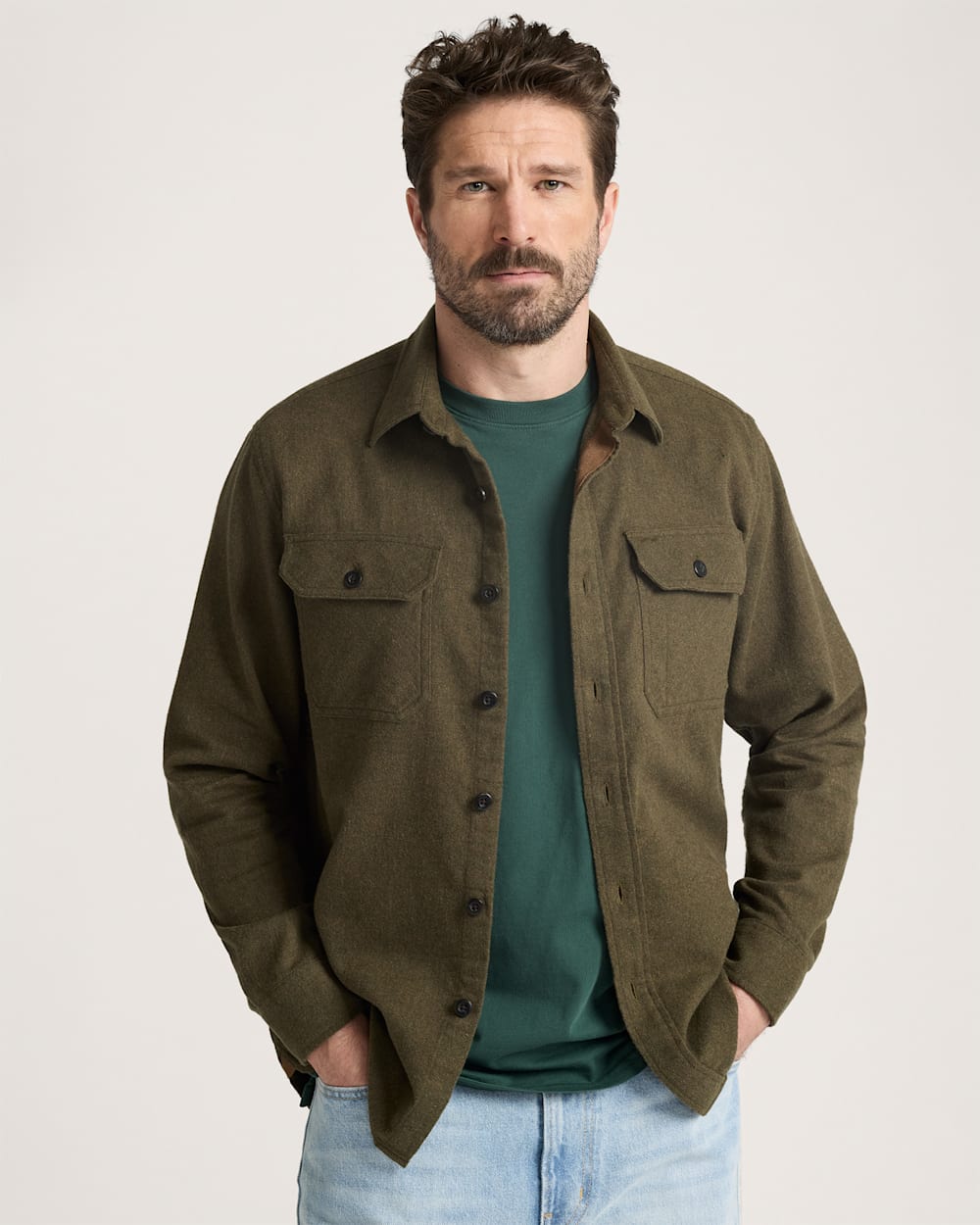 Man wearing a green jacket over a green shirt on a light gray background
