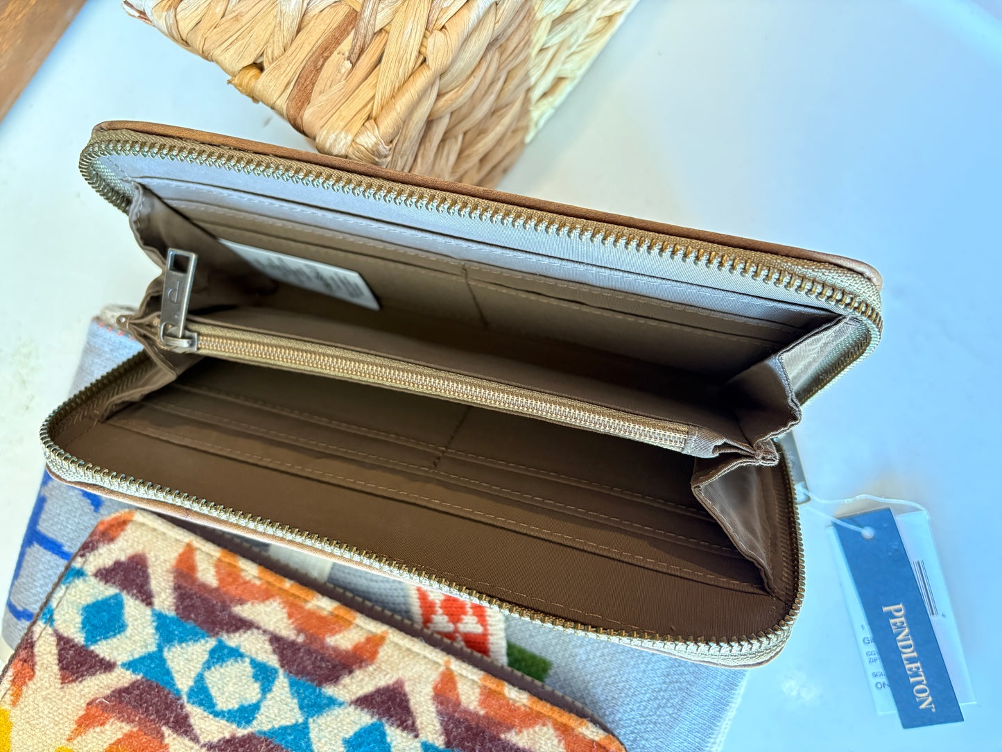 Open beige wallet on a colorful fabric background with a visible brand label.