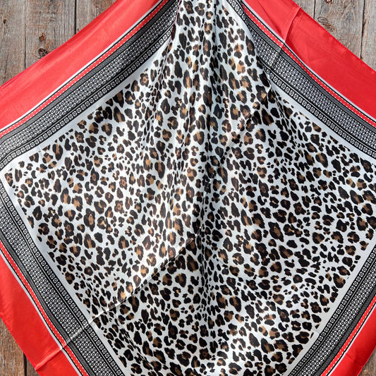Leopard print fabric with red border on wooden surface