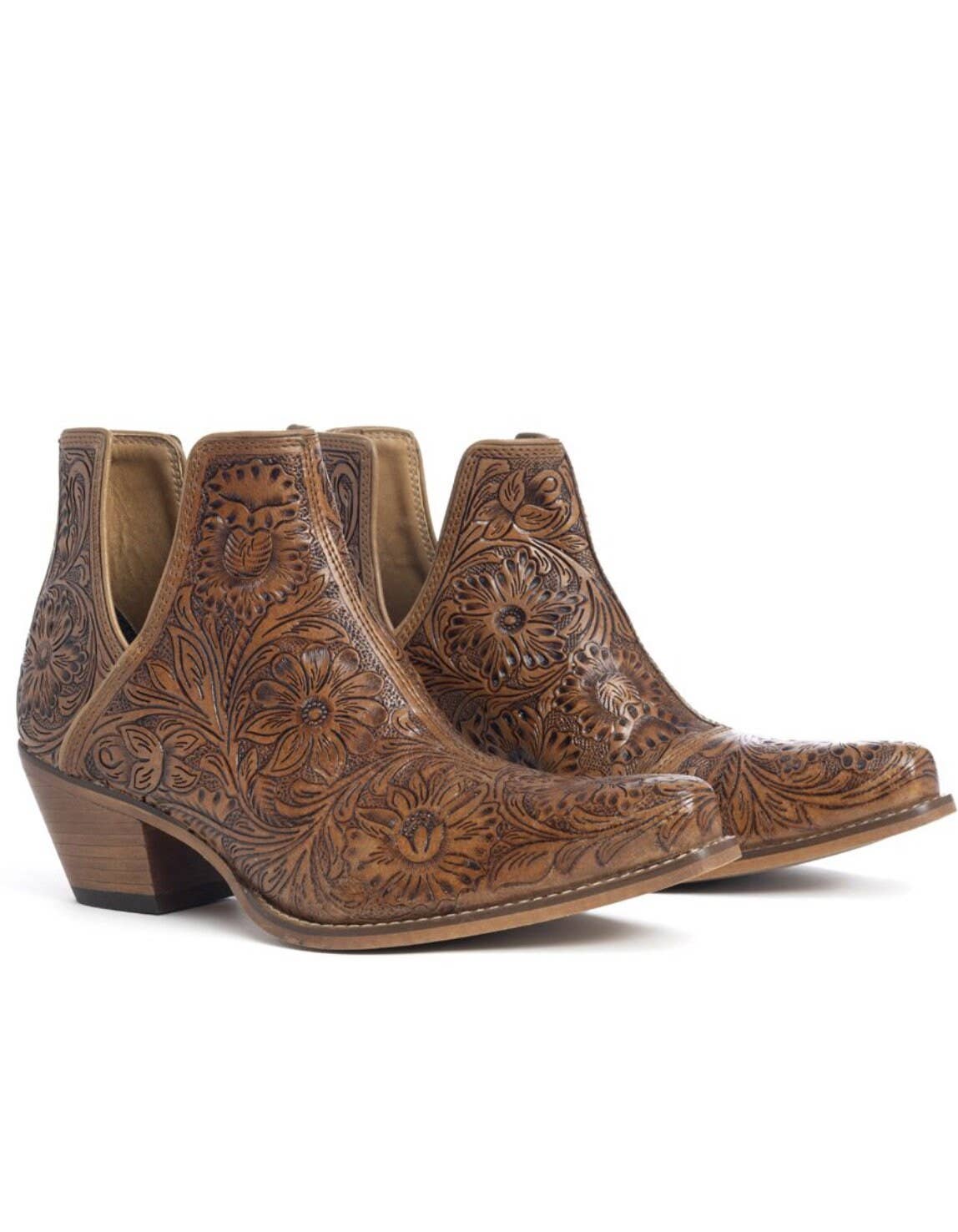 A pair of brown, hand-tooled booties with floral patterns.