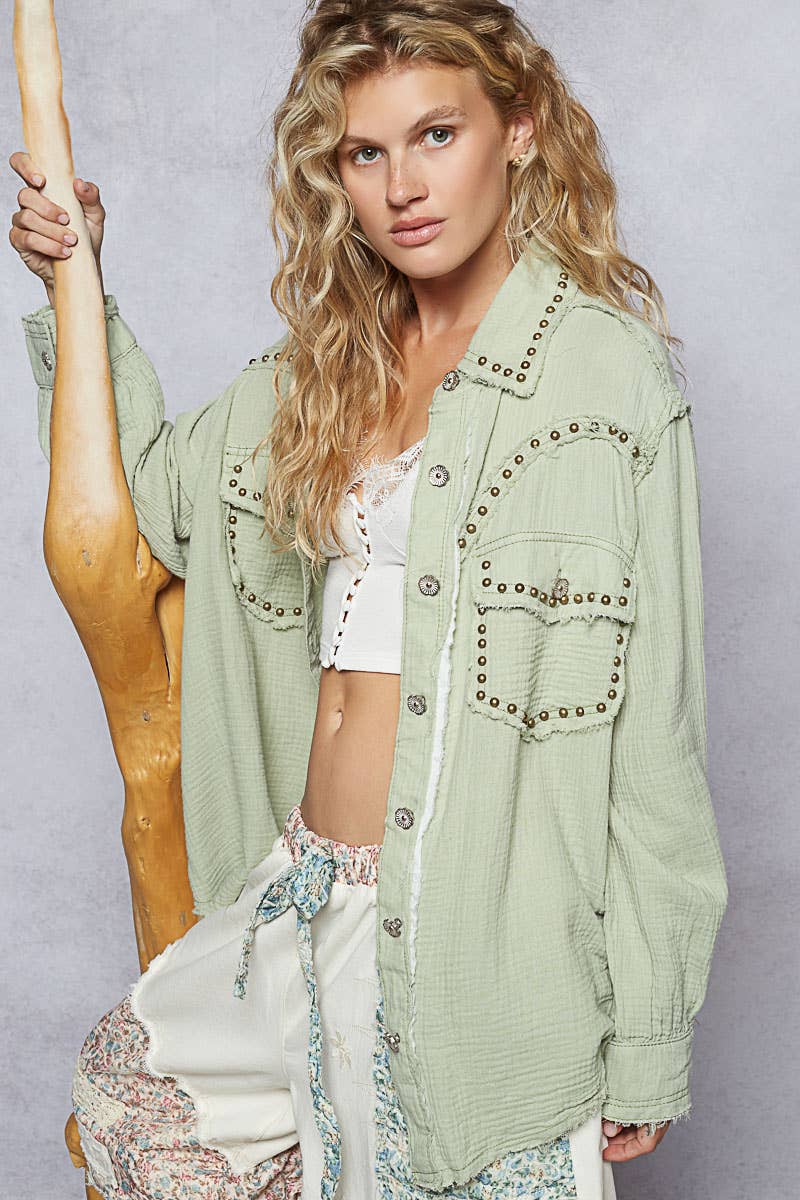 A woman wearing a long sleeve studded western style shirt top in green with collar and front button details.