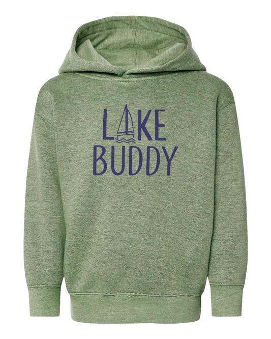 A child standing by the beach wearing a gray hoodie with the text 'LAKESIDE ADVENTURES' on it.