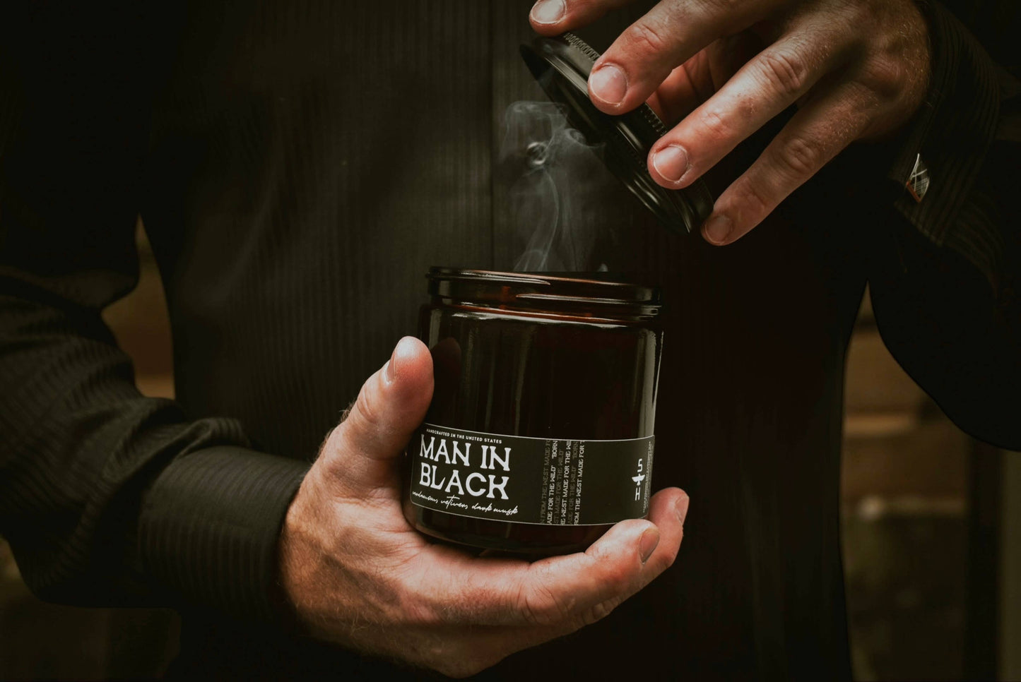 Person holding a jar labeled 'Man in Black' with a dark background