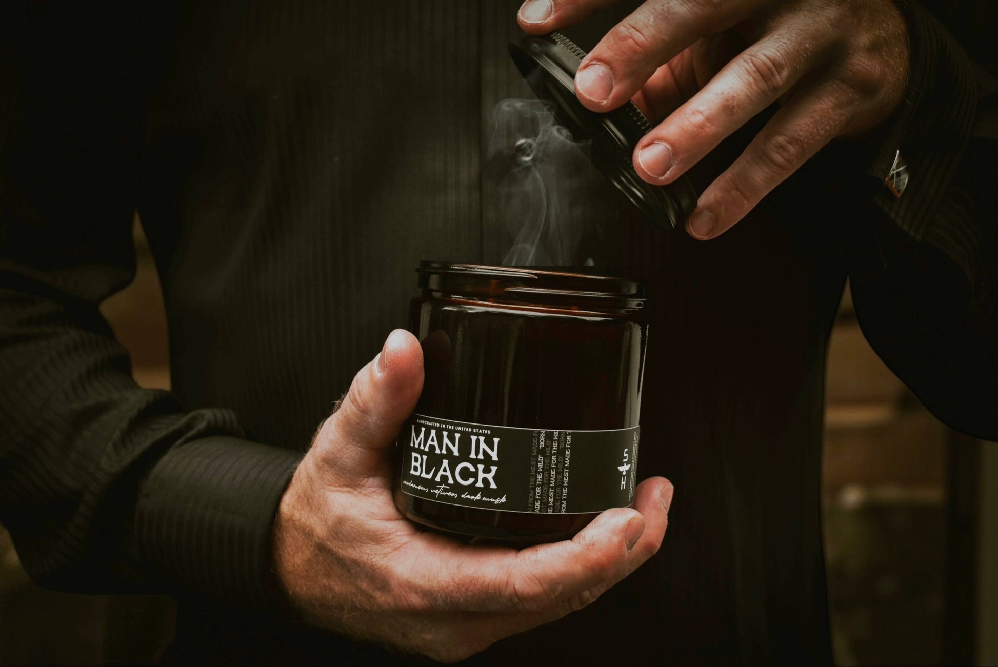 Person holding a jar labeled 'Man in Black' with a dark background